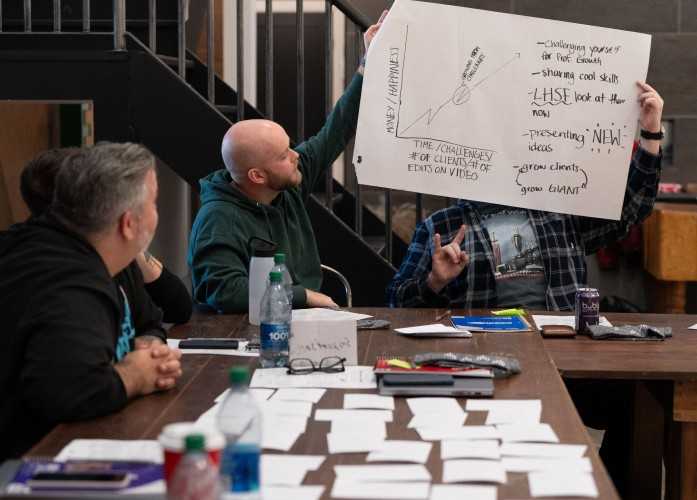 two employees sitting at a table and holding up a image of a graph