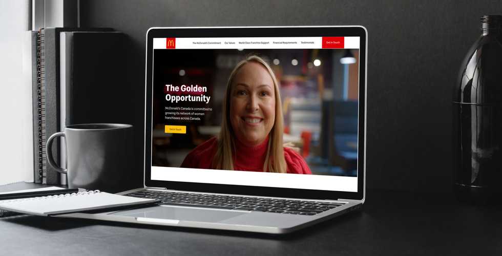 laptop on a desk with books and a mug looking at the McDonalds Franchise landing page