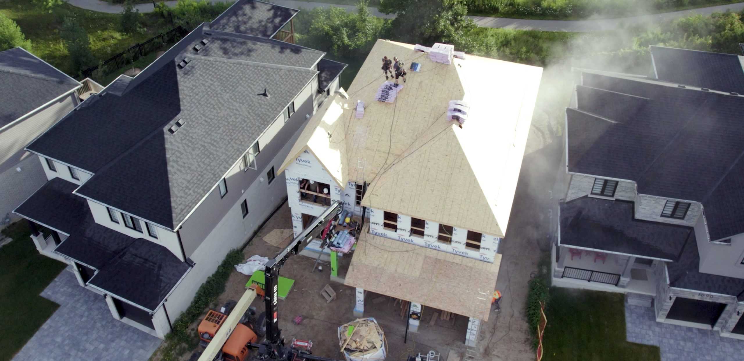 a birds-eye view of a house with workers giving a new roof