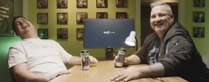 Andrew and Marty having a drink at a desk and smiling